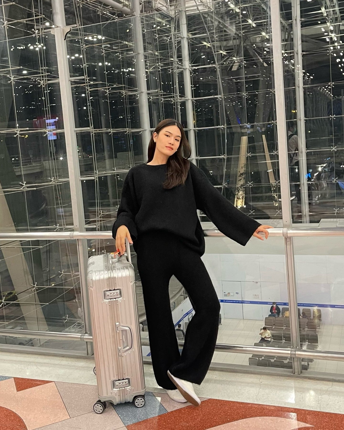woman with a suitcase in an indoor setting with reflective surfaces