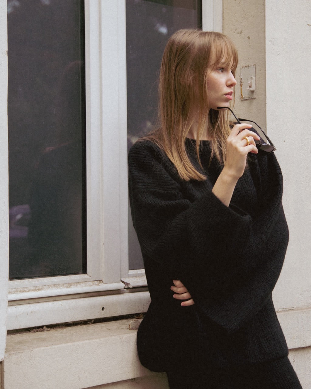 Woman wearing a black sweater standing by a window