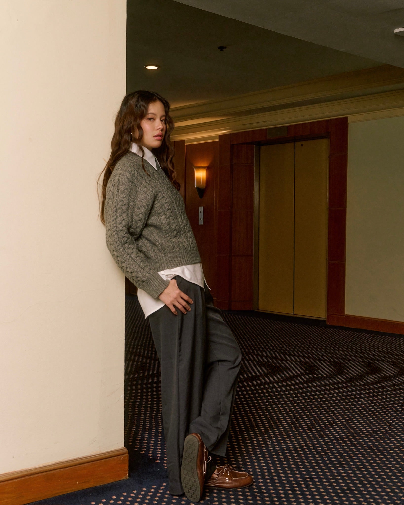 woman leaning against a wall in an indoor setting