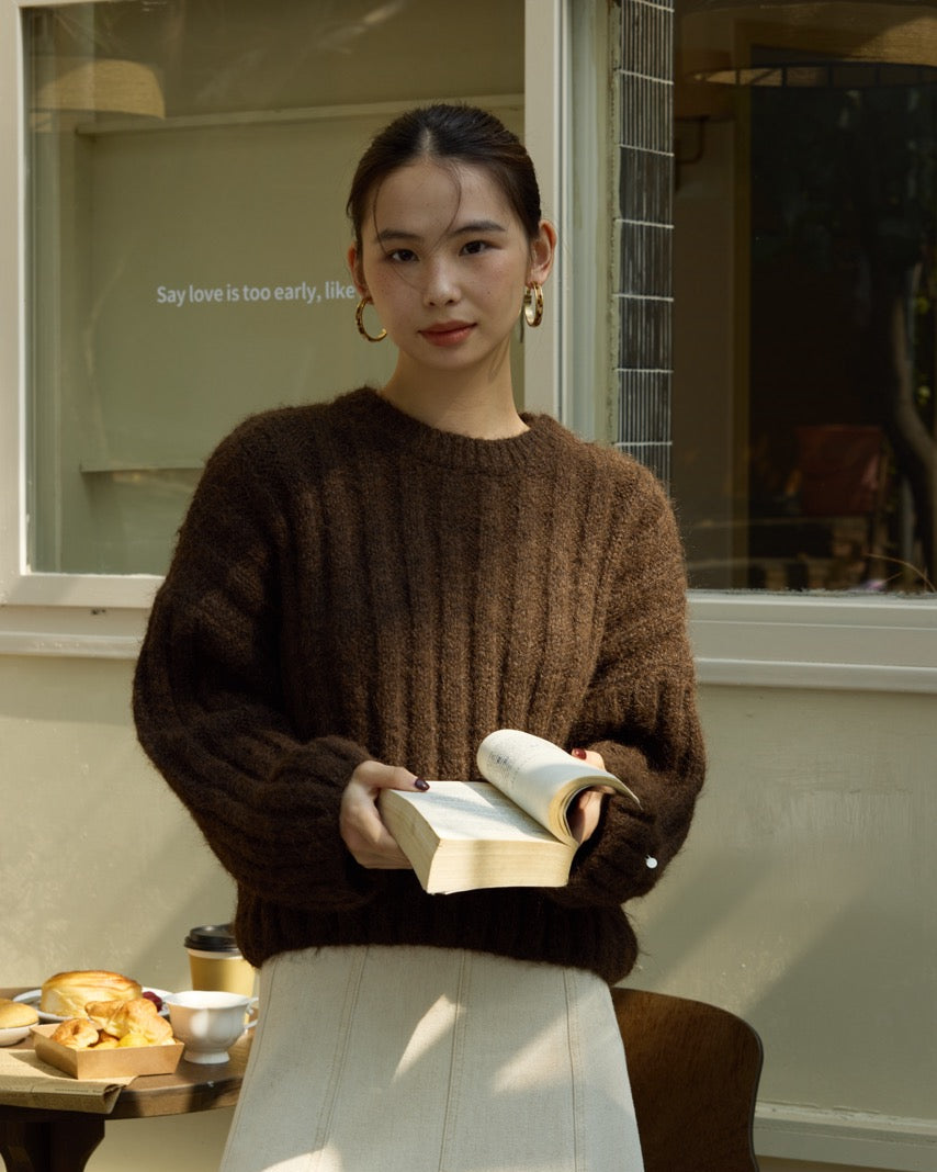 Woman holding a book in an indoor setting with a table and window in the background