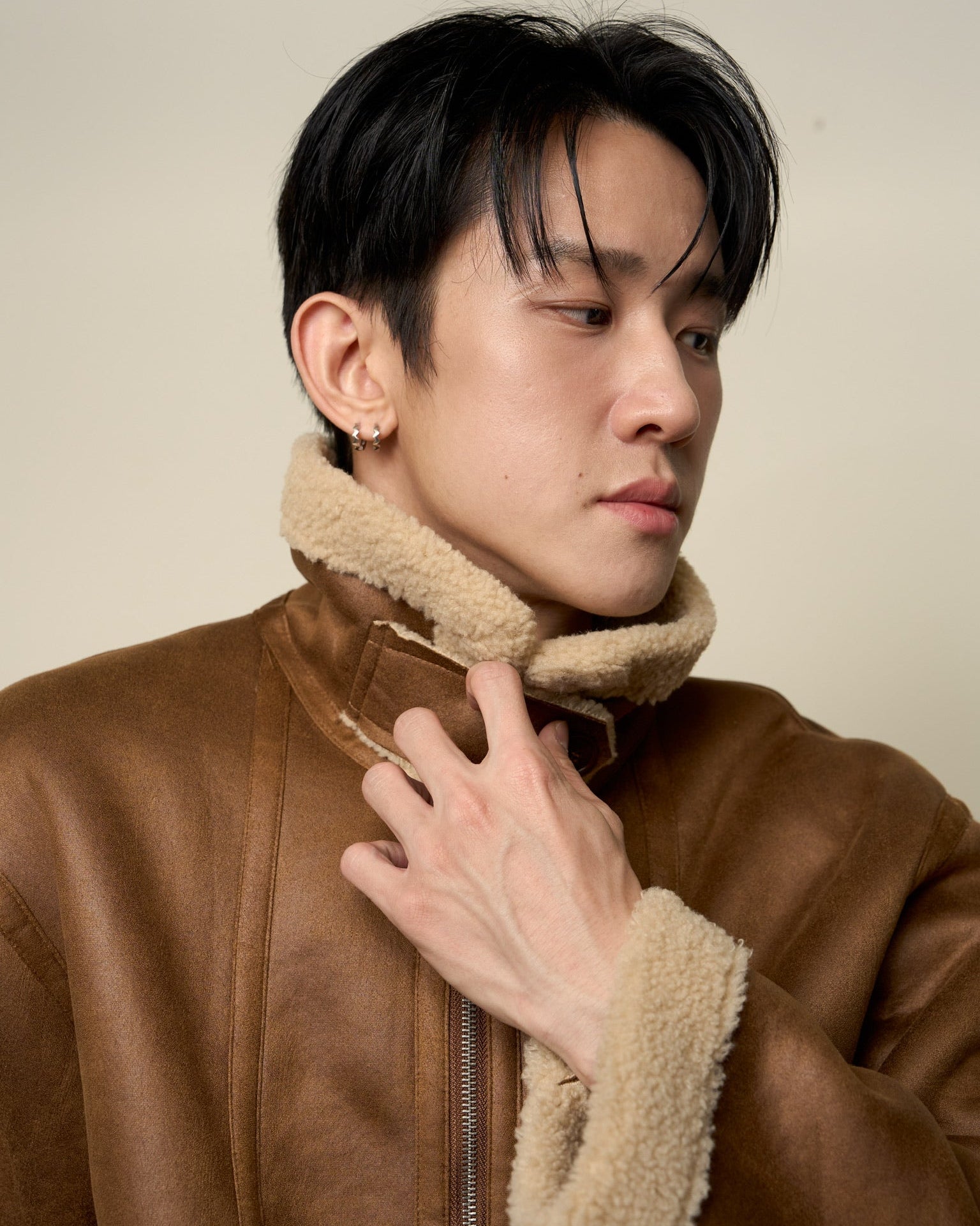 Man wearing a brown jacket with a fur-lined hood against a plain background