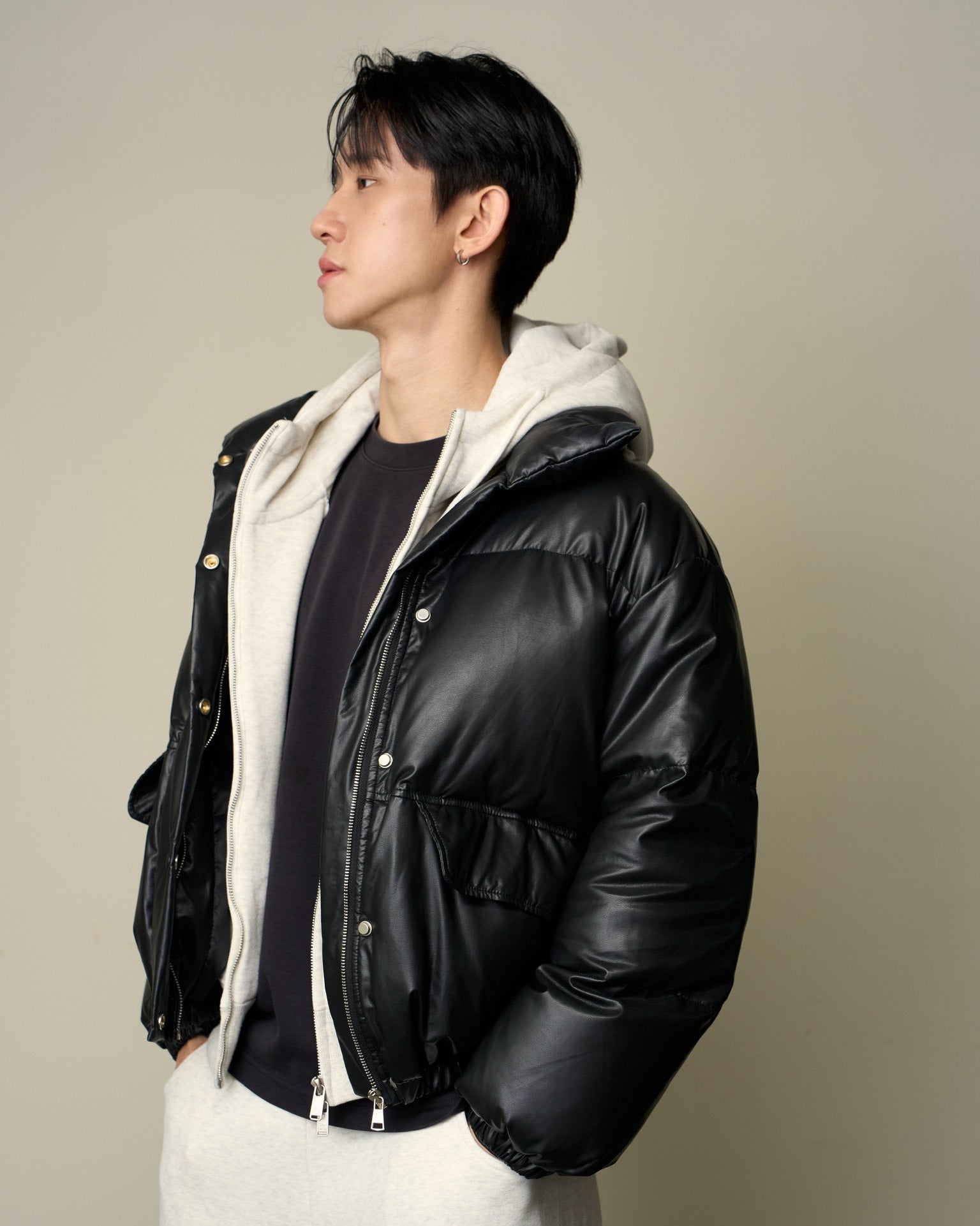 woman wearing a black leather jacket with a white hood against a plain background