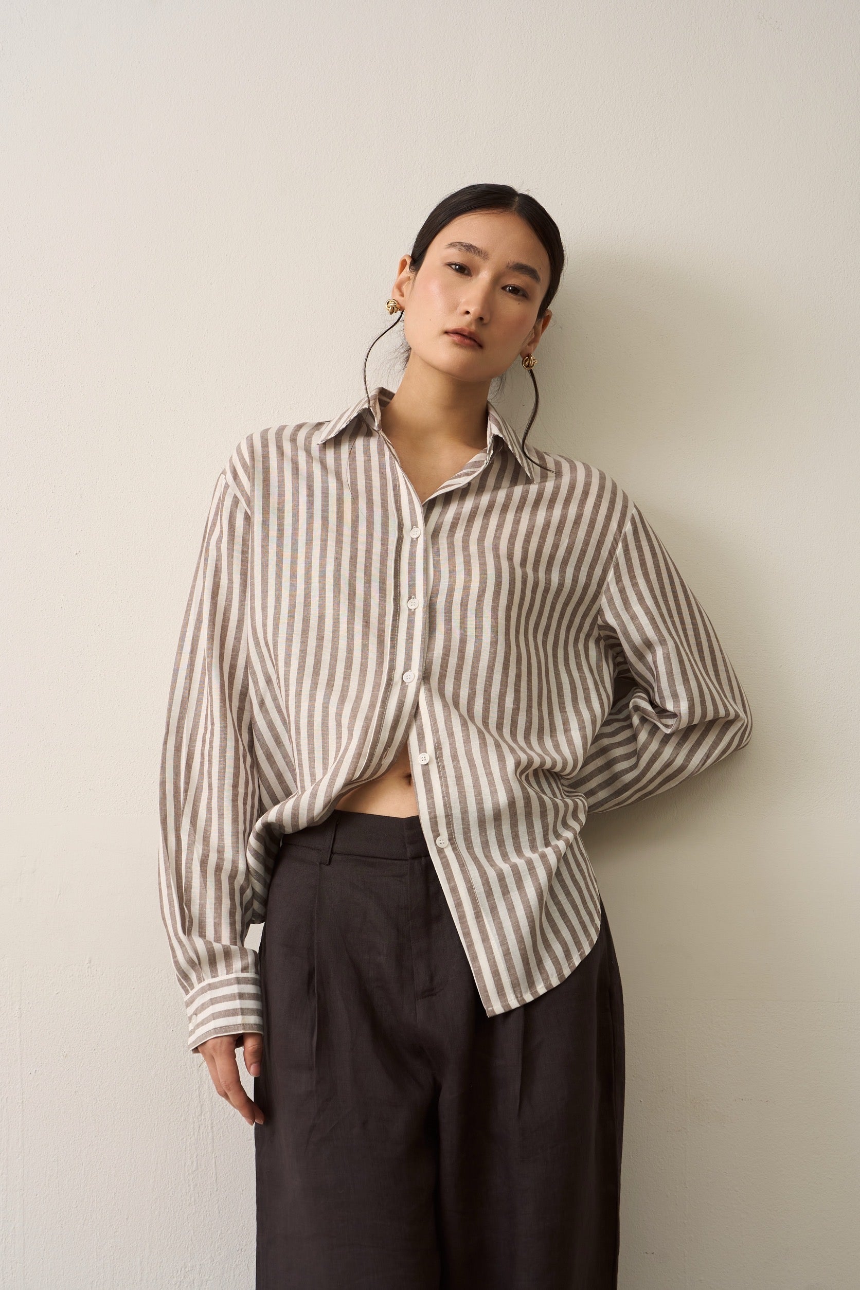 Women wearing brown striped long sleeves linen shirt in plain background