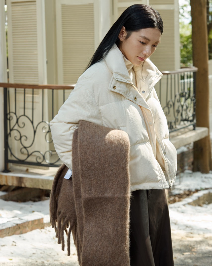 Woman wearing a white puffer jacket and brown scarf in an outdoor setting