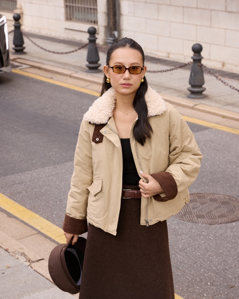 Woman wearing a beige jacket with fur lining on a city street