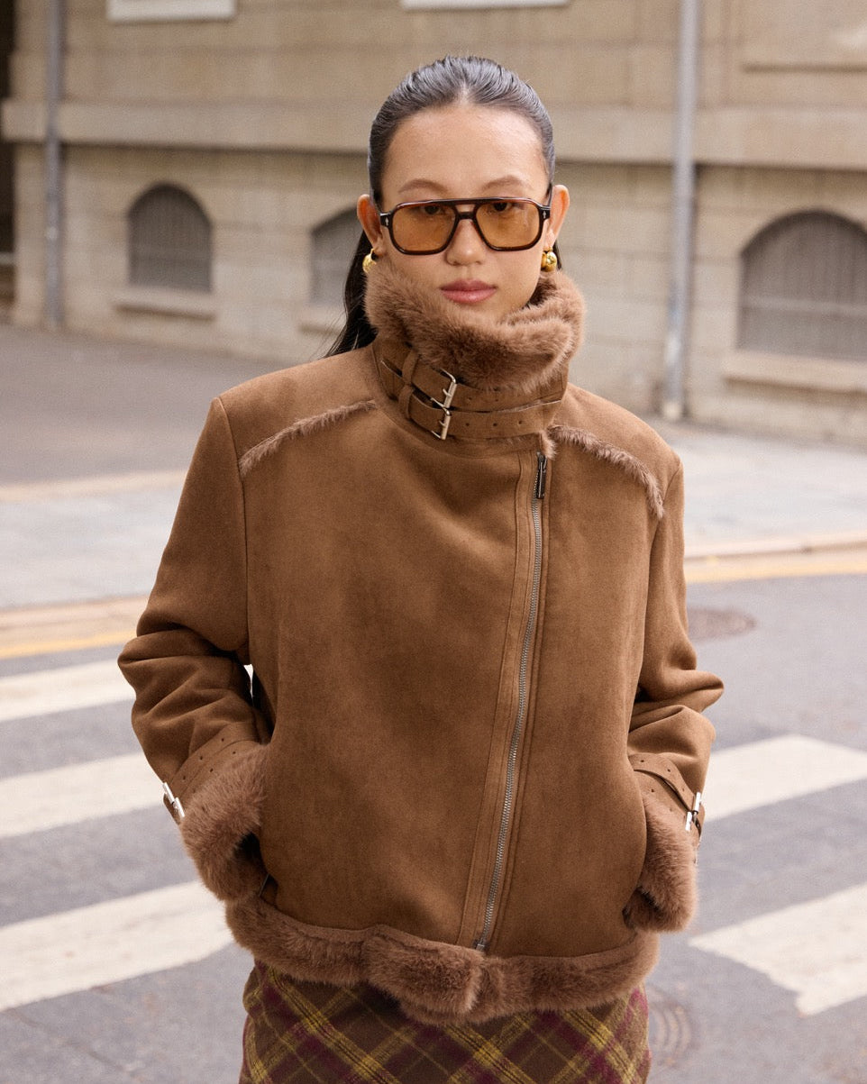 woman wearing a brown shearling jacket on a street.