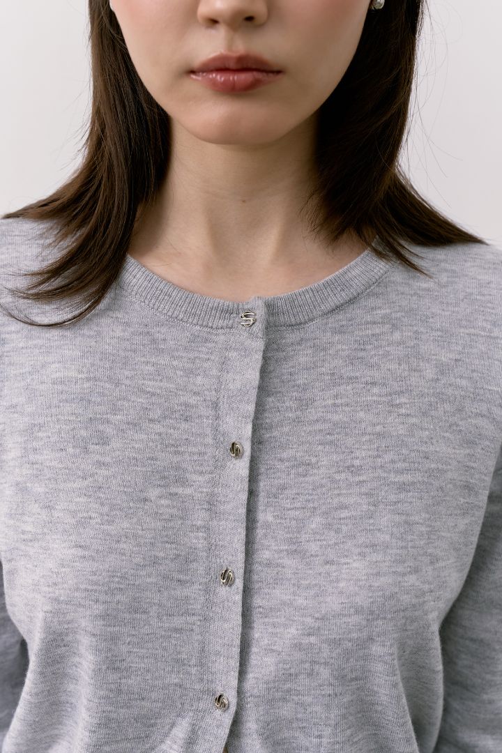 Close-up of a woman wearing a gray  Double S Cardigan with a button front.