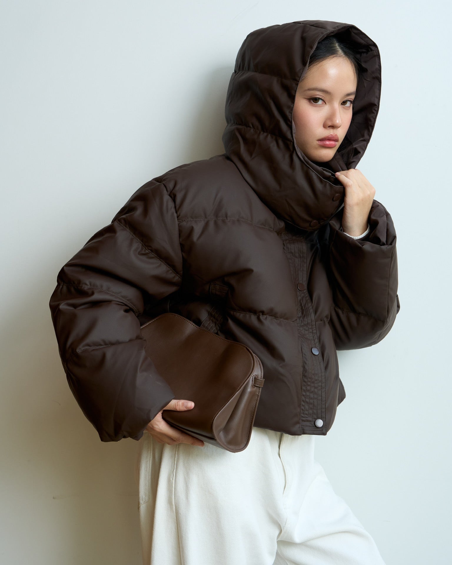 woman wearing a brown puffer jacket against a white background