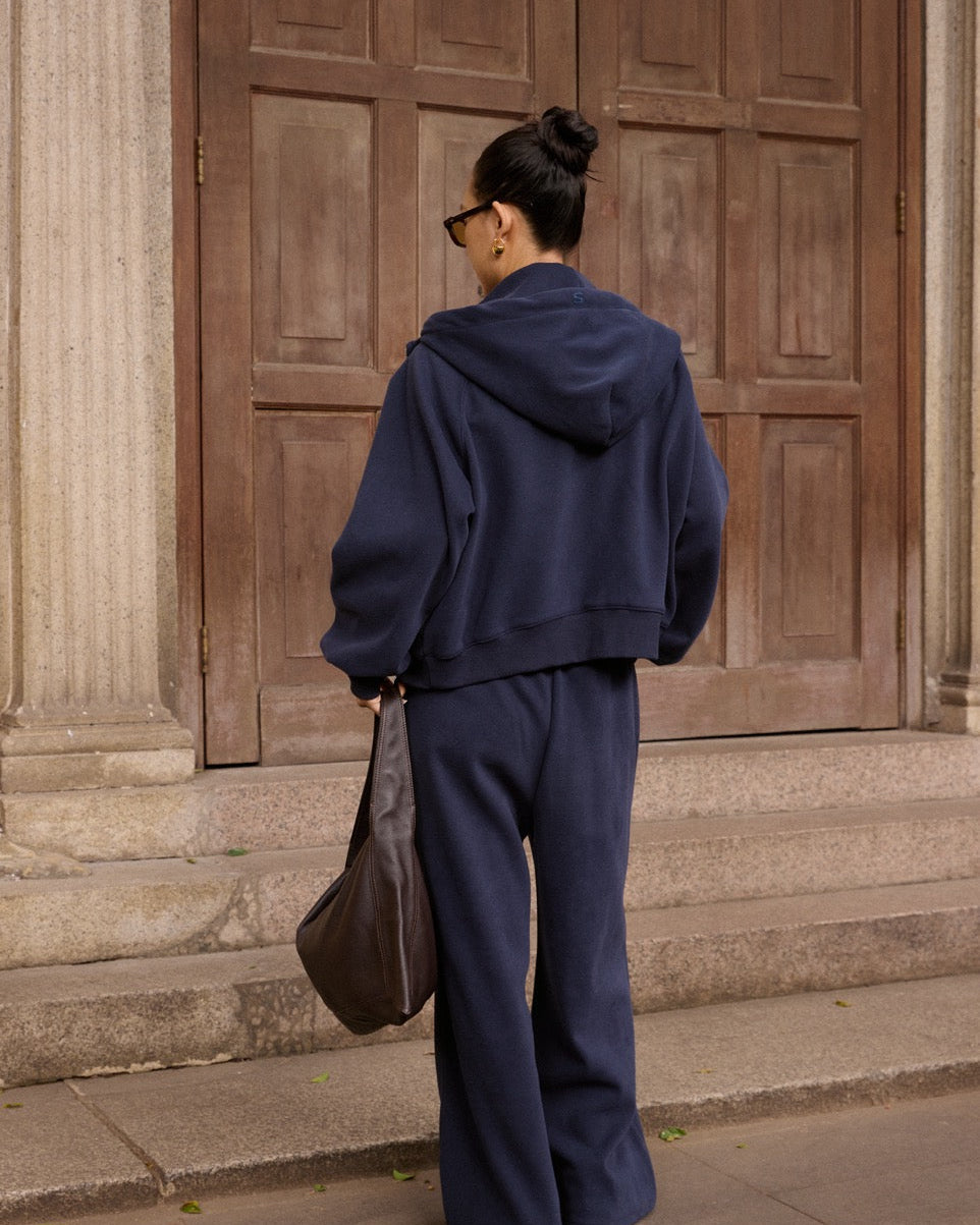 woman wearing a navy tracksuit standing in front of wooden doors.
