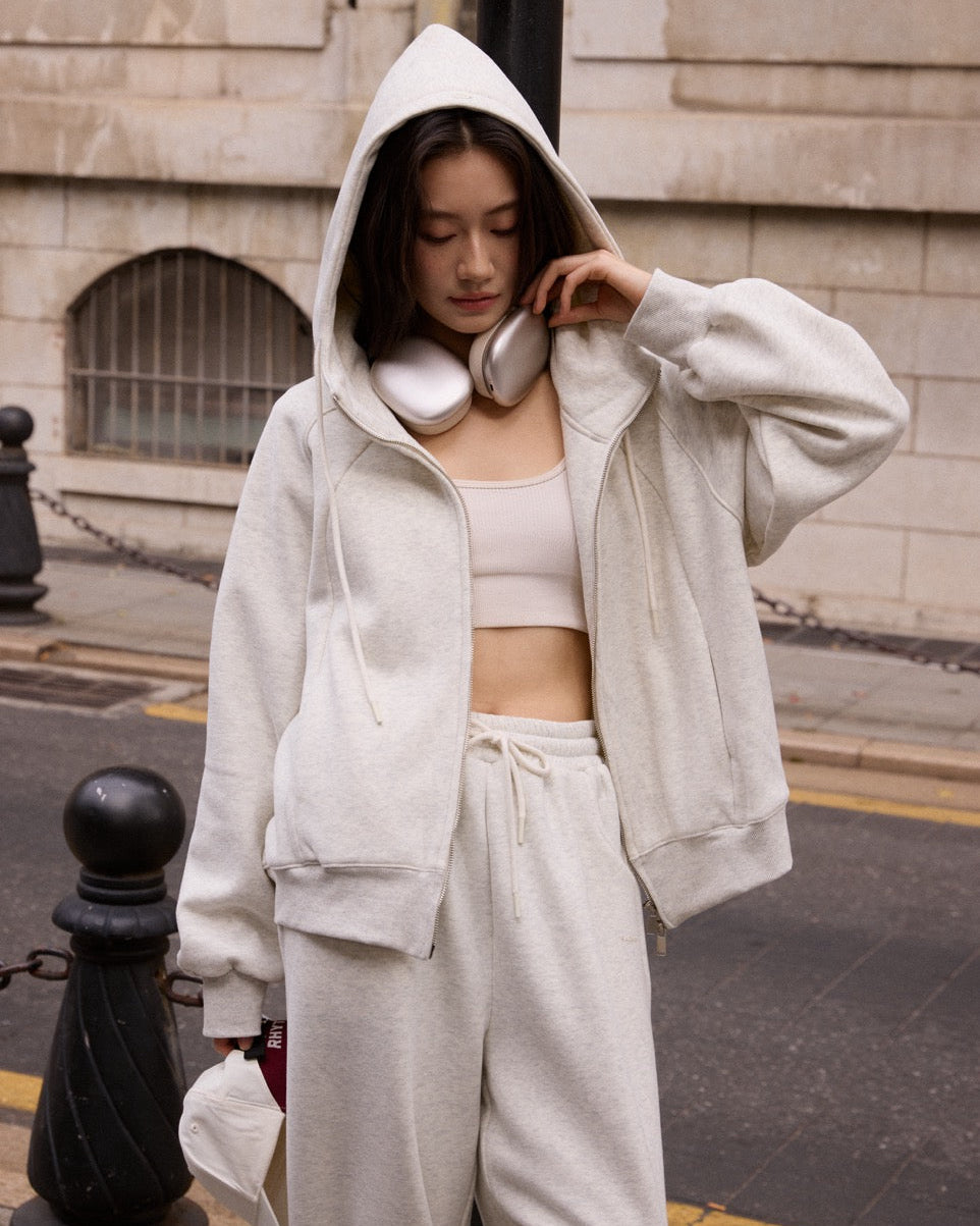 woman wearing a white hoodie and pants on a city street.