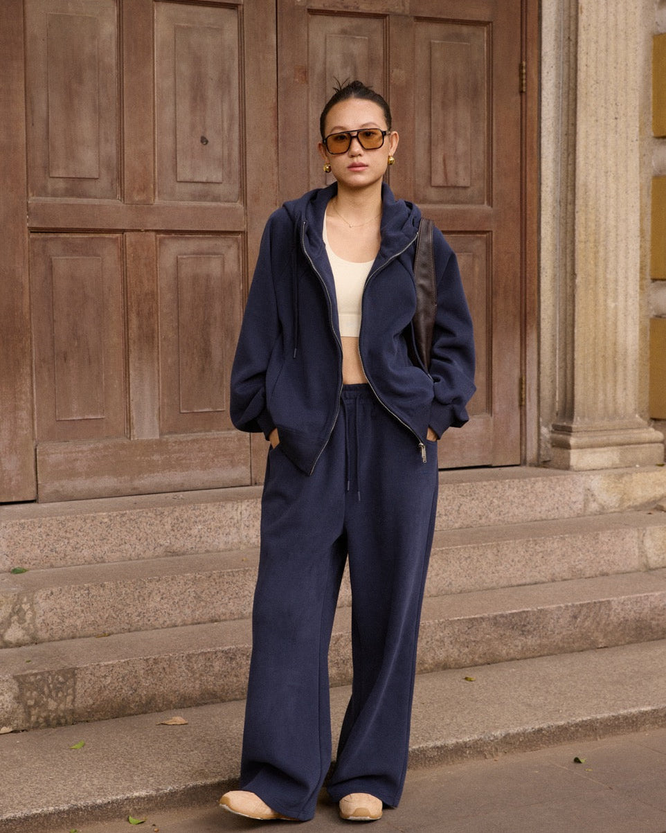 Woman in navy blue outfit standing on steps with wooden doors in the background