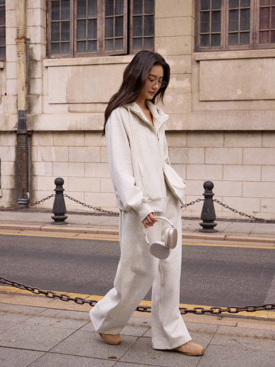 Woman in a white outfit walking on a street with a building in the background