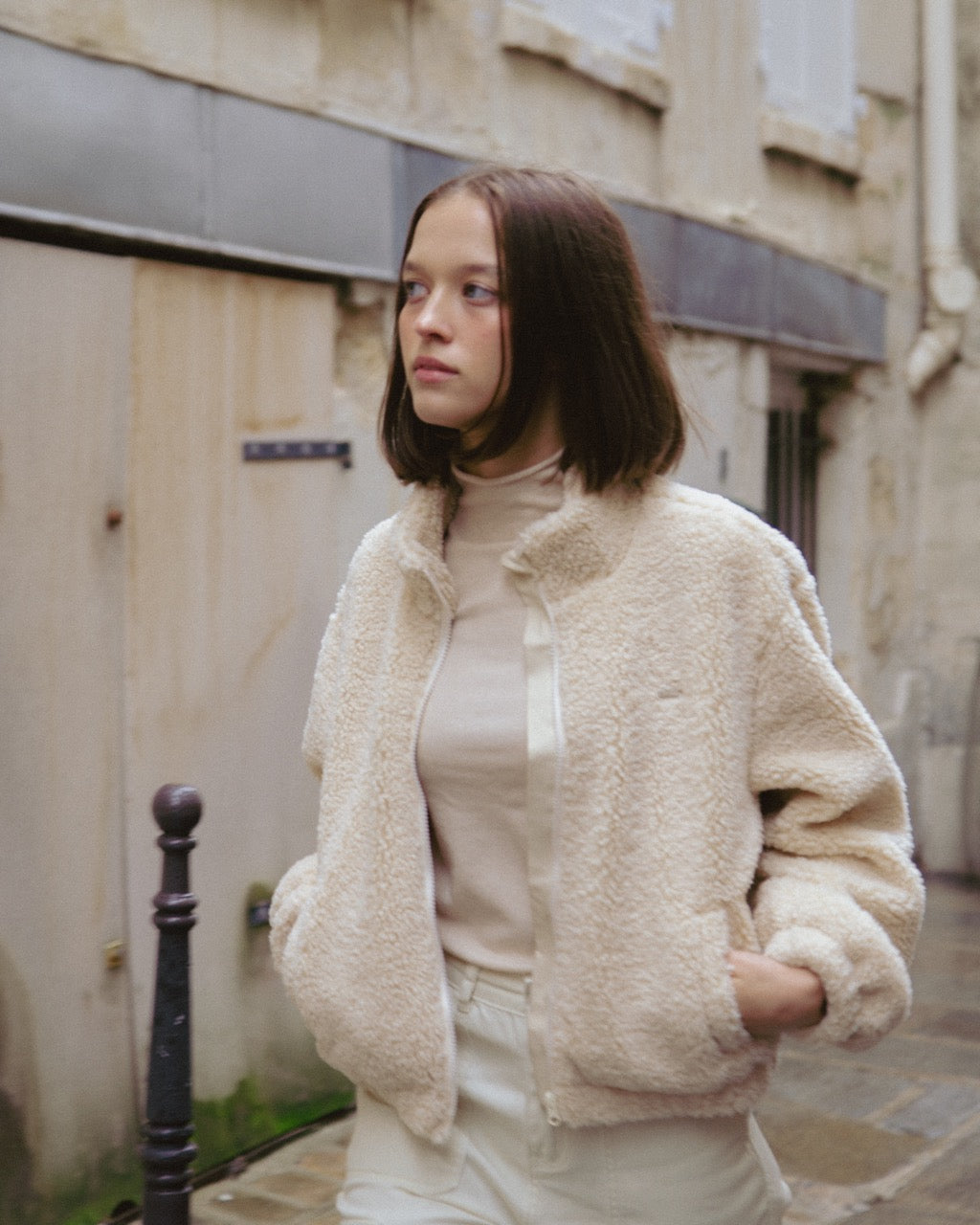 Woman wearing a cream-colored jacket in an urban setting