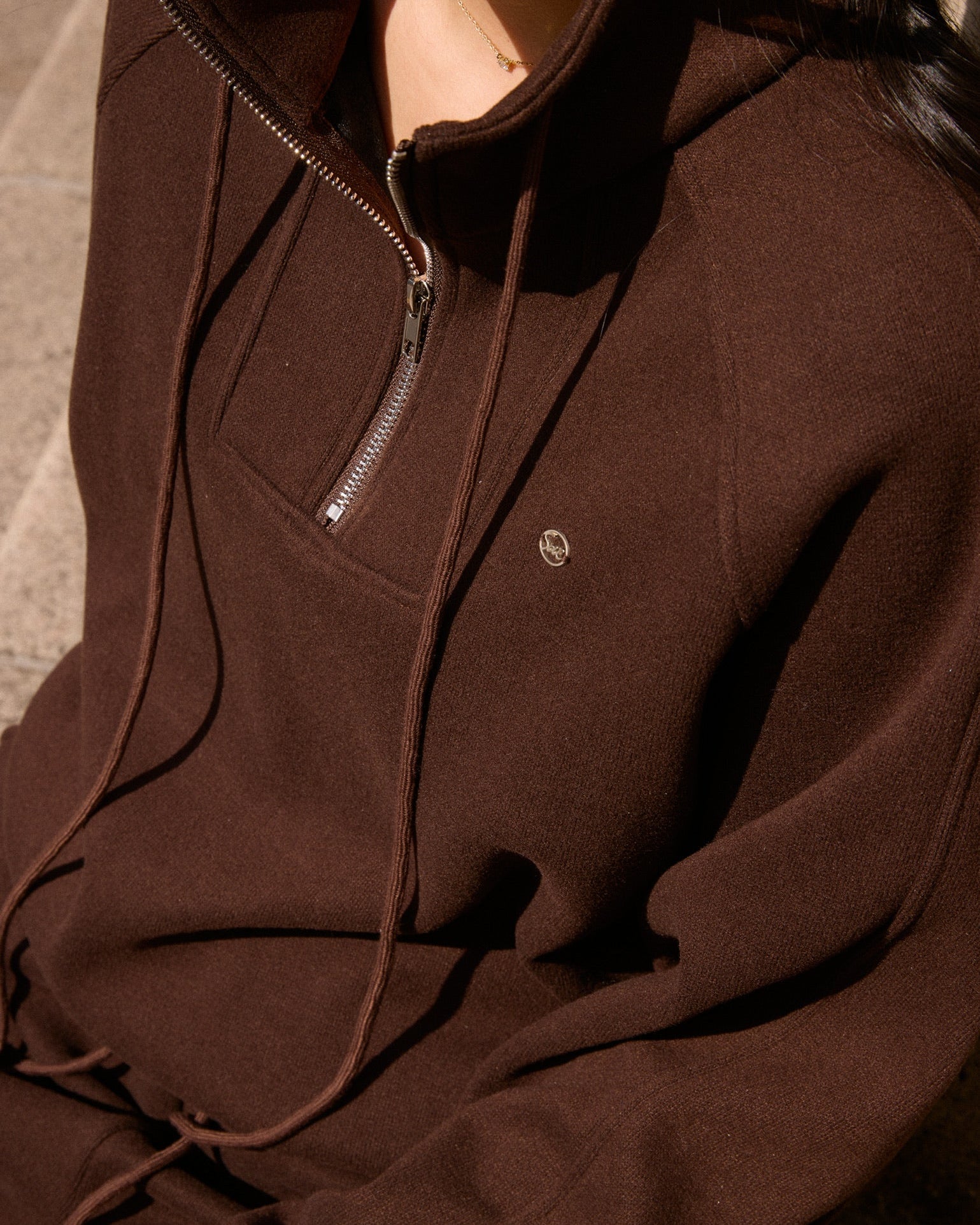 Brown hoodie with a zipper on a neutral background