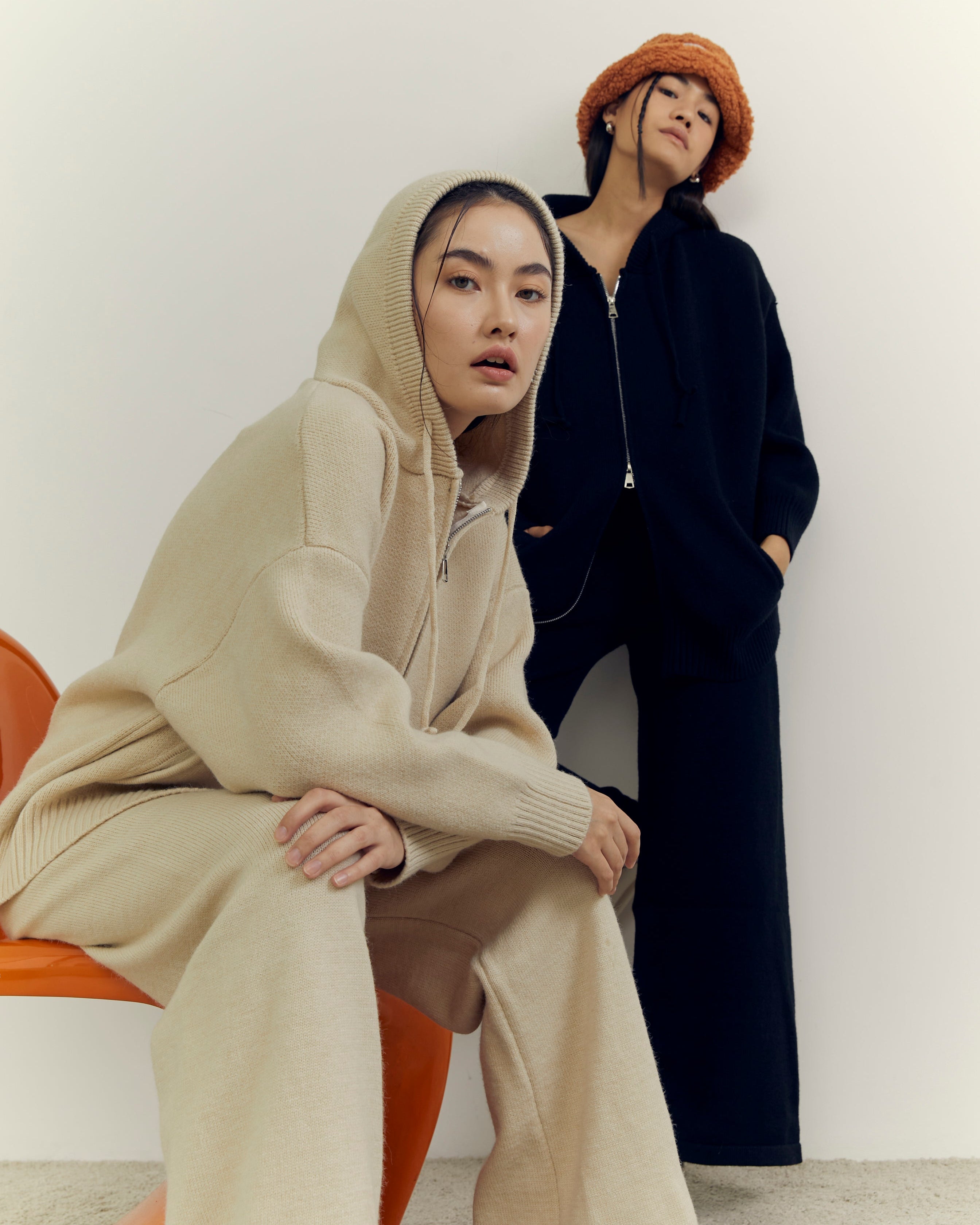 Two women wearing hoodies in a minimalistic setting