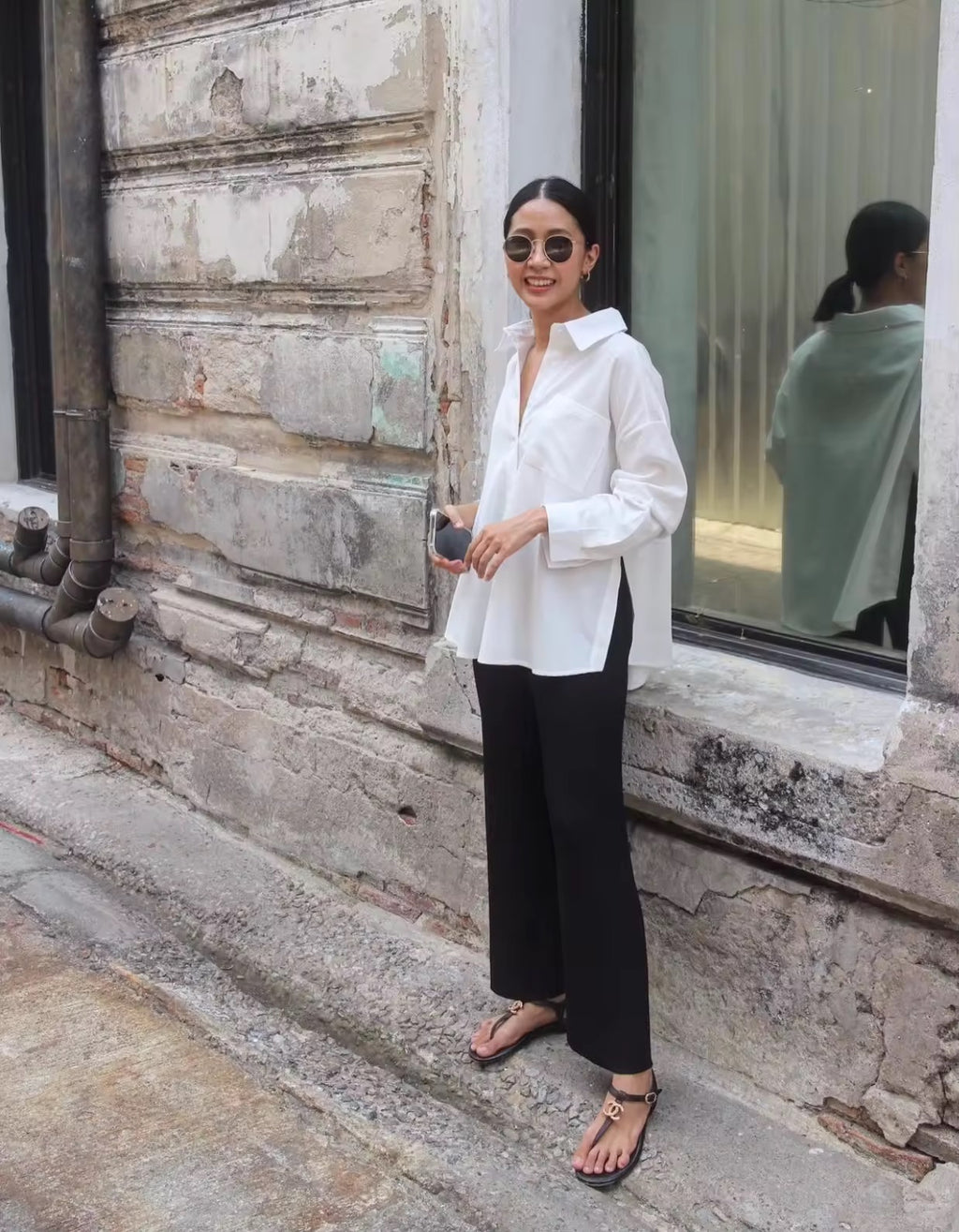 Woman in a white shirt and black pants standing on a stone staircase.