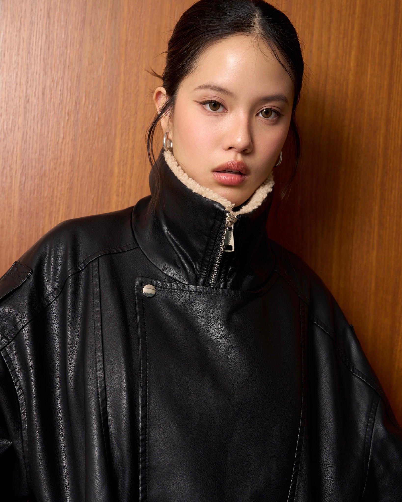 woman wearing a black leather jacket against a wooden background