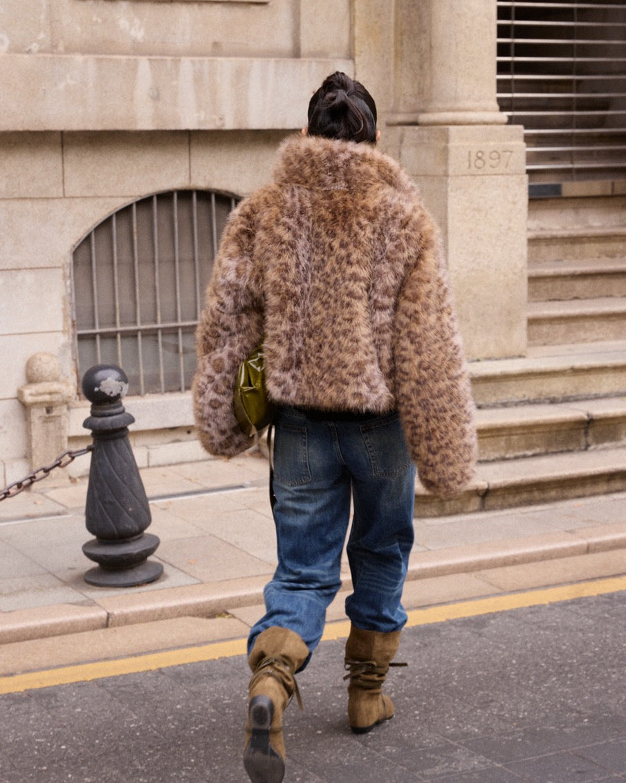 woman wearing a fluffy brown coat walking on a street.