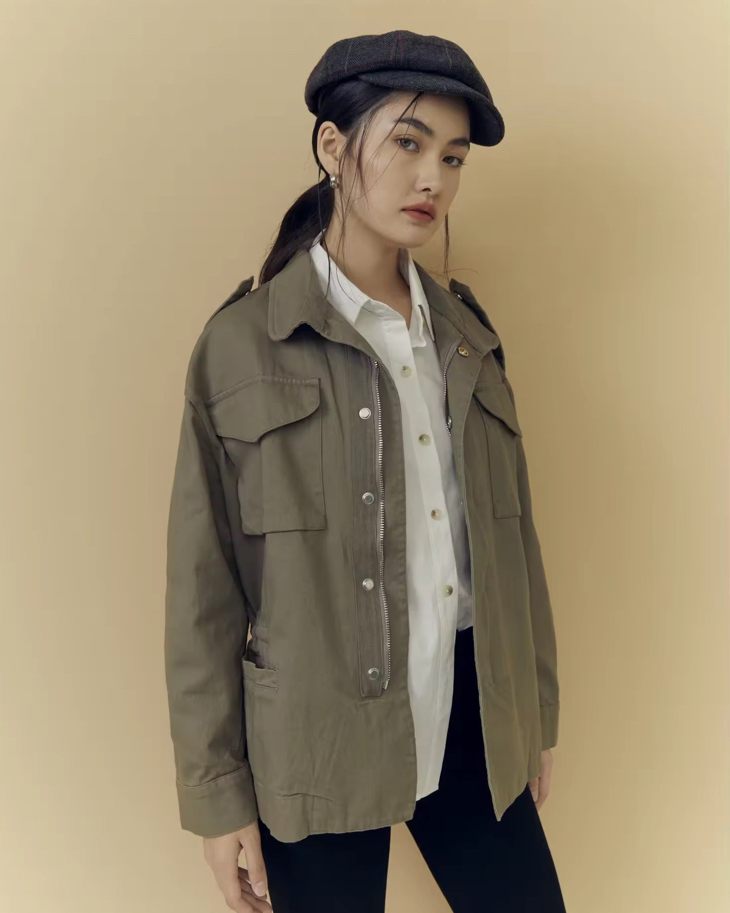 Woman wearing a green jacket and cap against a beige background