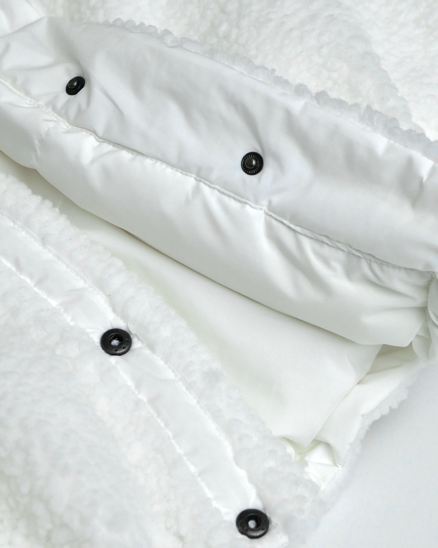 Close-up of a white textured fabric with black buttons