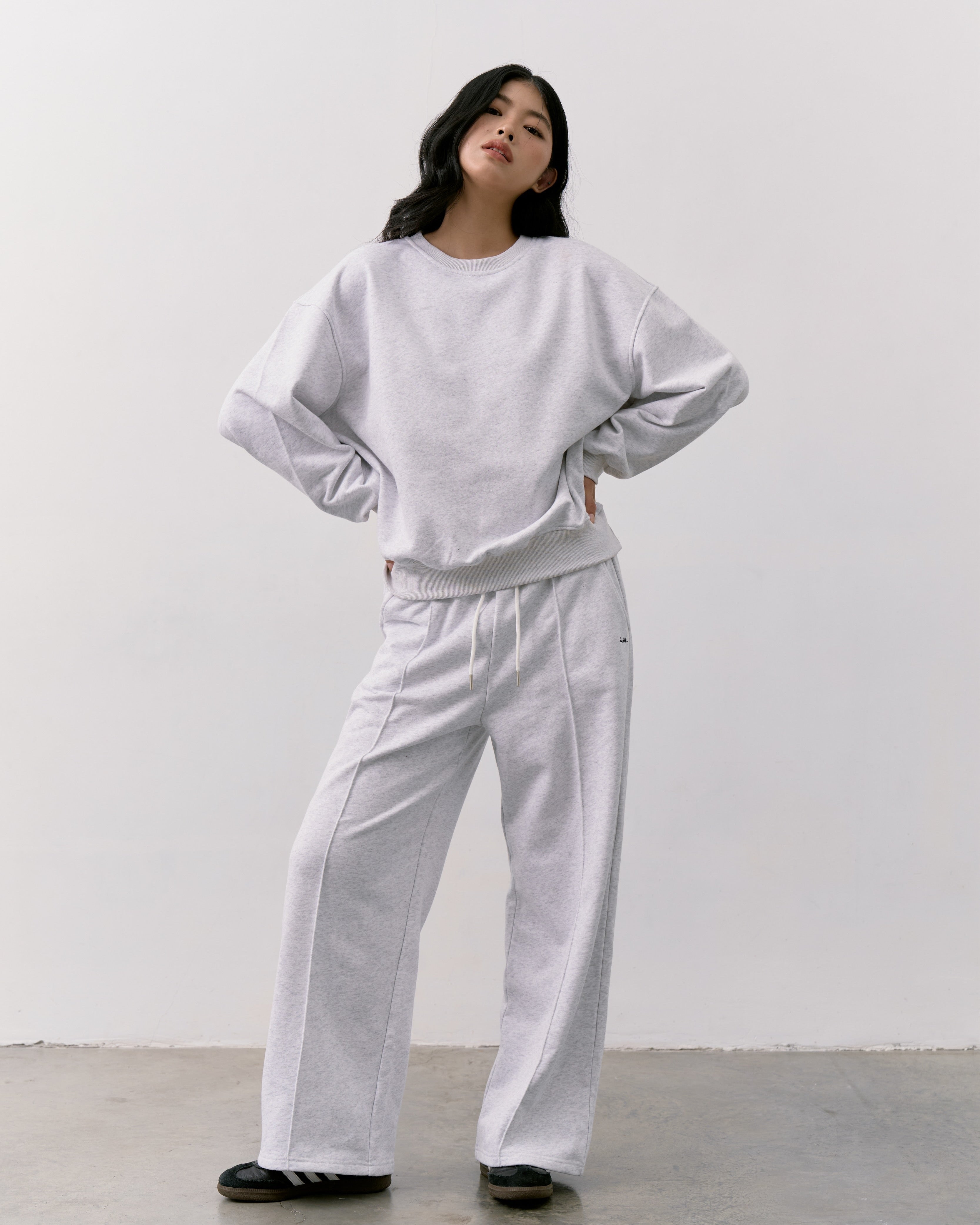 woman wearing a light gray outfit against a white background
