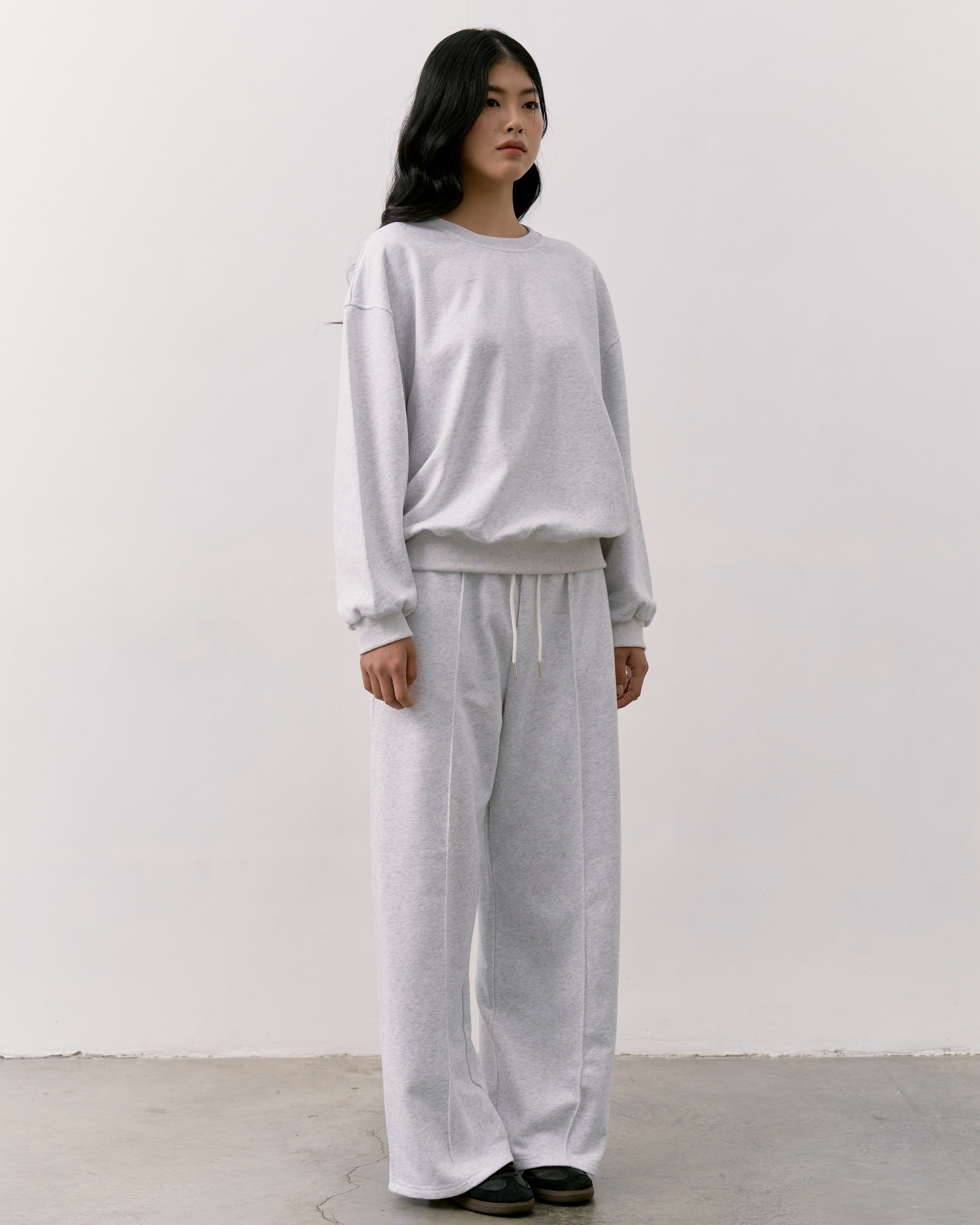 woman wearing a gray outfit standing against a white background