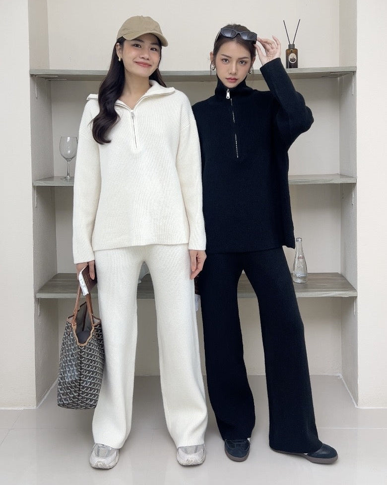 Two women standing side by side in a minimalistic room with white walls and shelves.