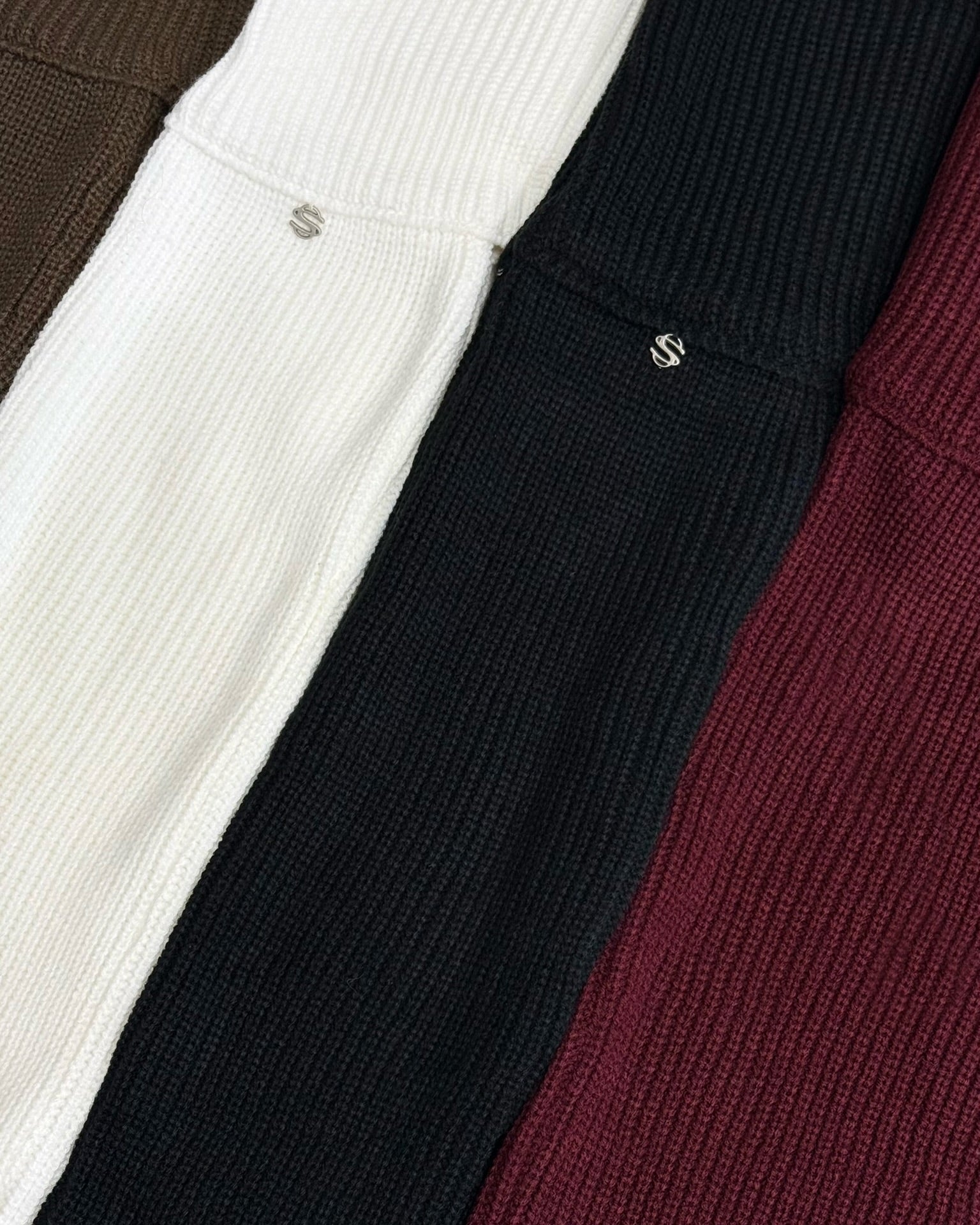Four different colored sweaters arranged in a row.