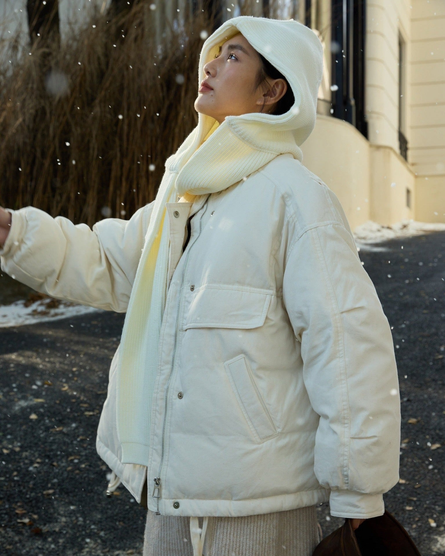 woman wearing a white coat and scarf in a snowy outdoor setting