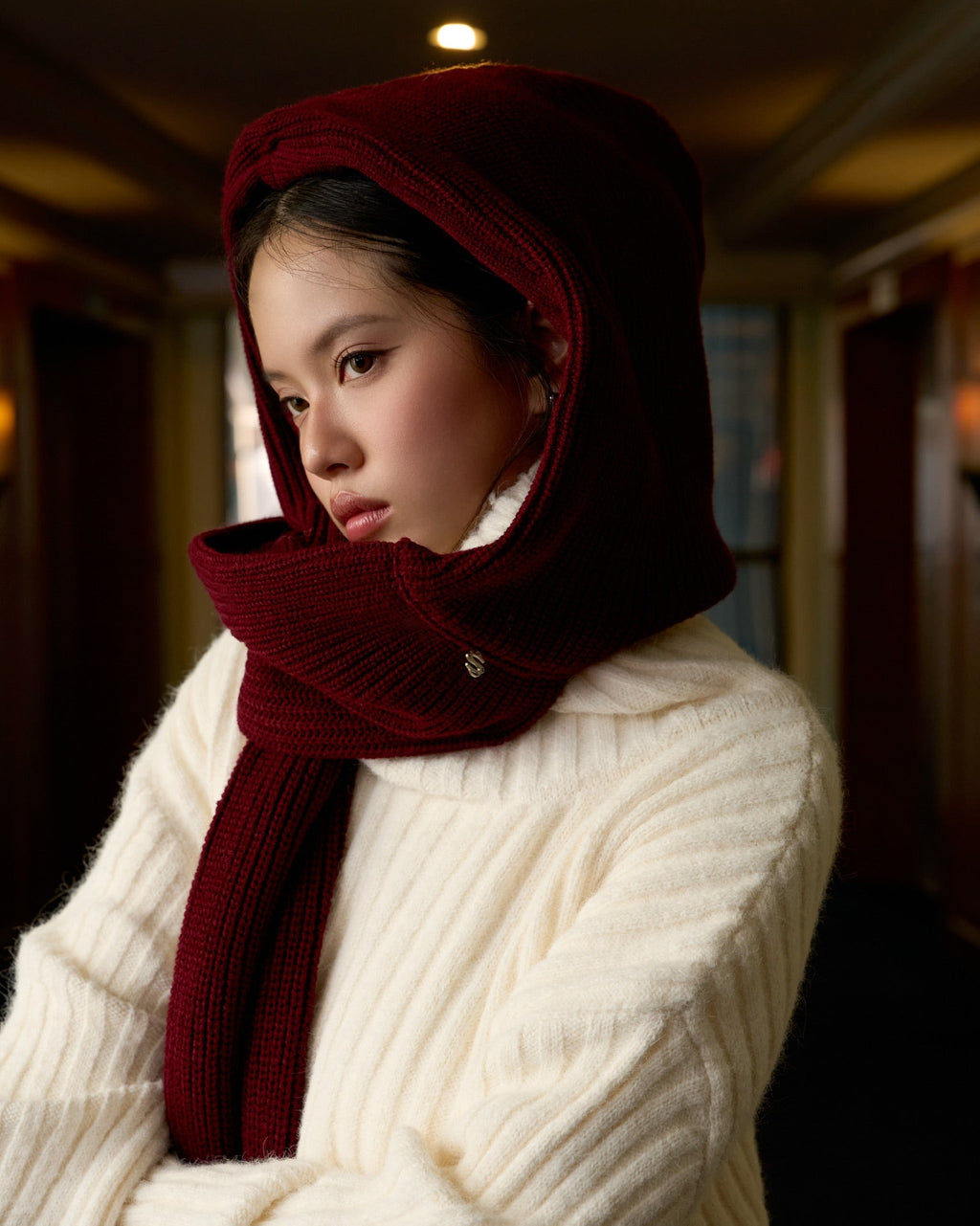 woman wearing a red scarf and white sweater in an indoor setting