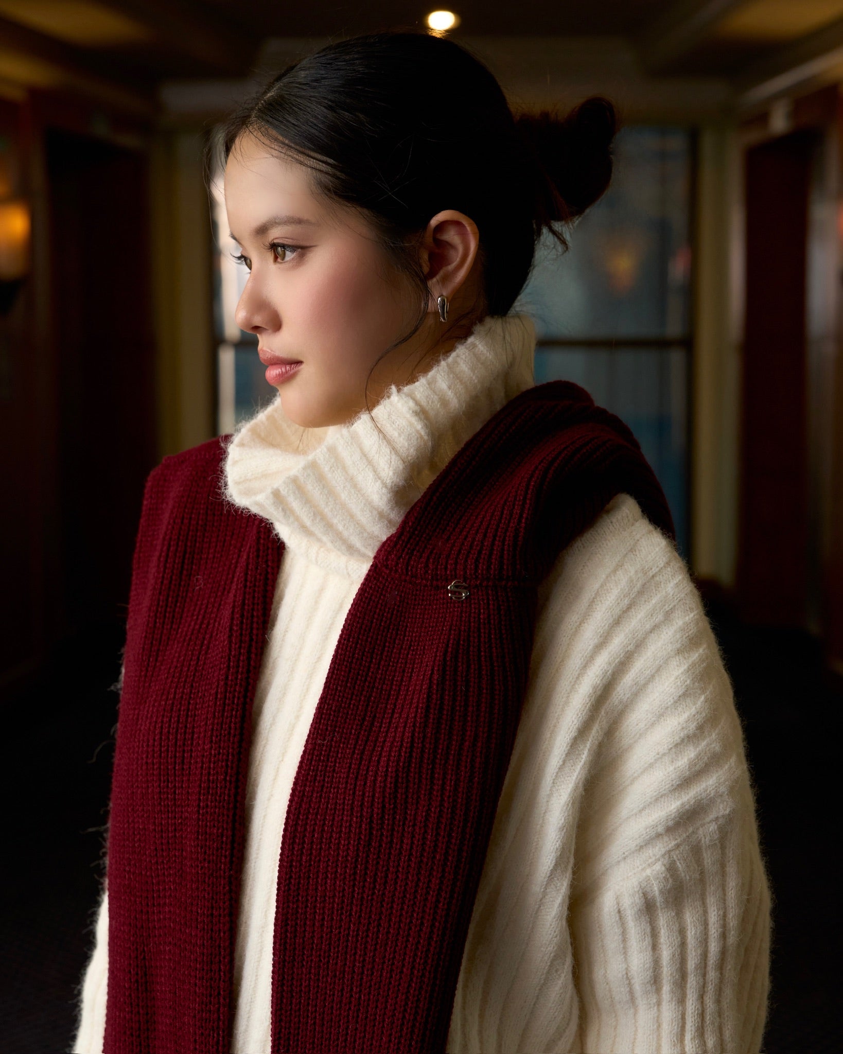 Woman wearing a white turtleneck and red vest indoors