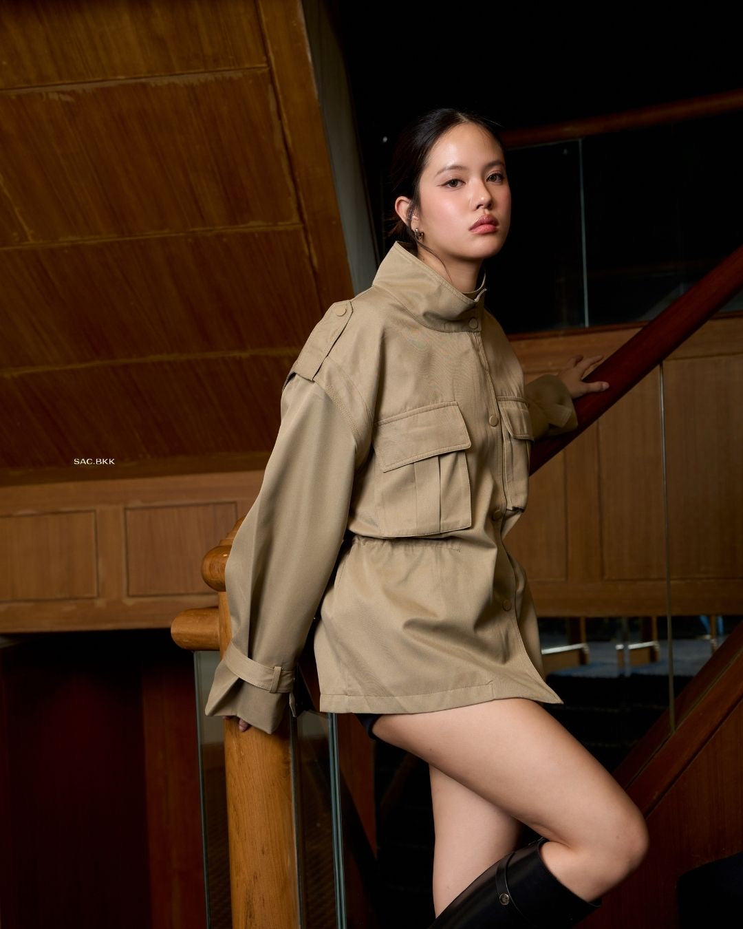 Woman in a olive green outfit sitting on a wooden staircase.