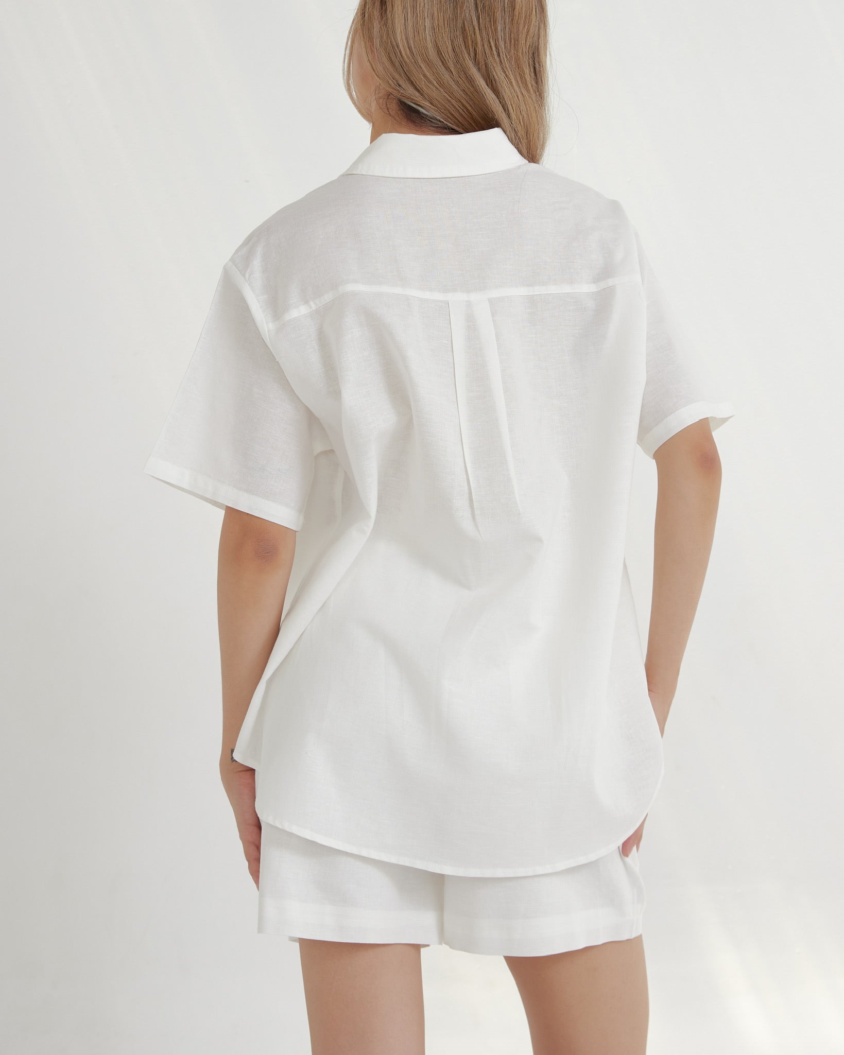 woman wearing a white shirt and shorts set on a light gray background