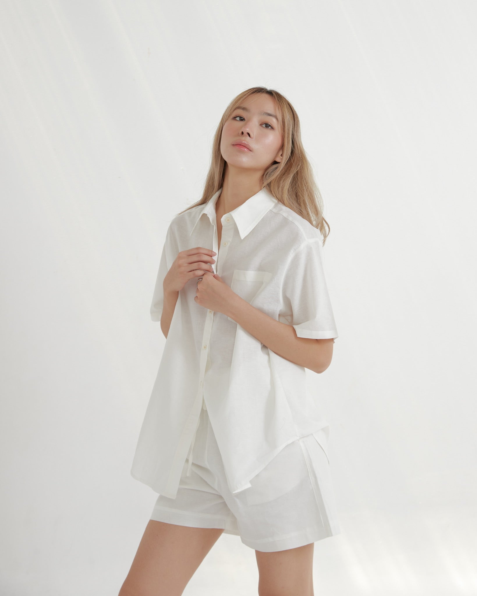 Woman wearing a white shirt and shorts on a plain background